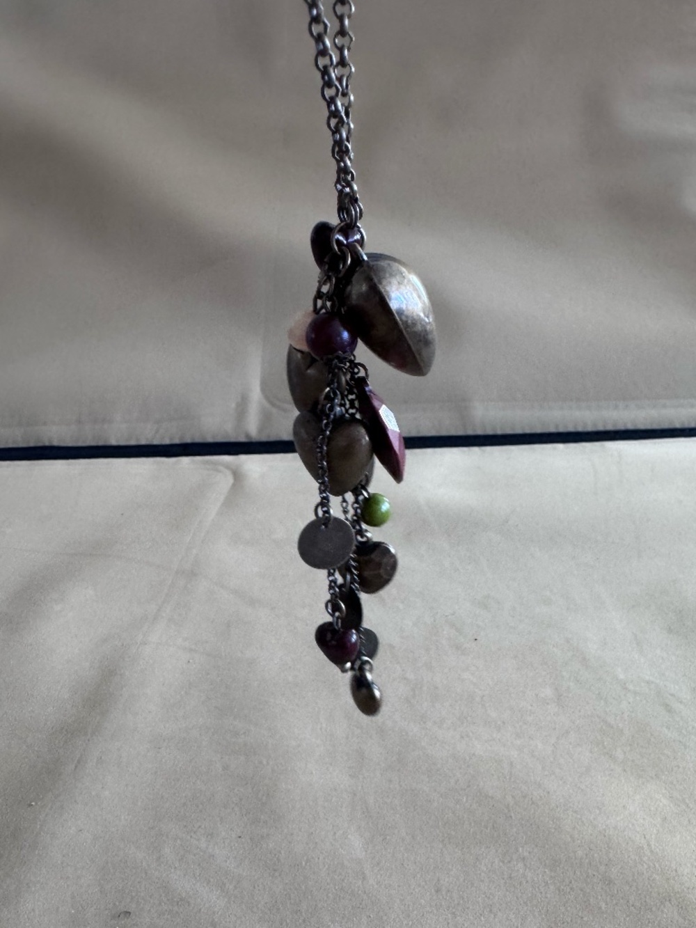 Pendant necklace with a dark metal chain and a cluster of beads and heart charms